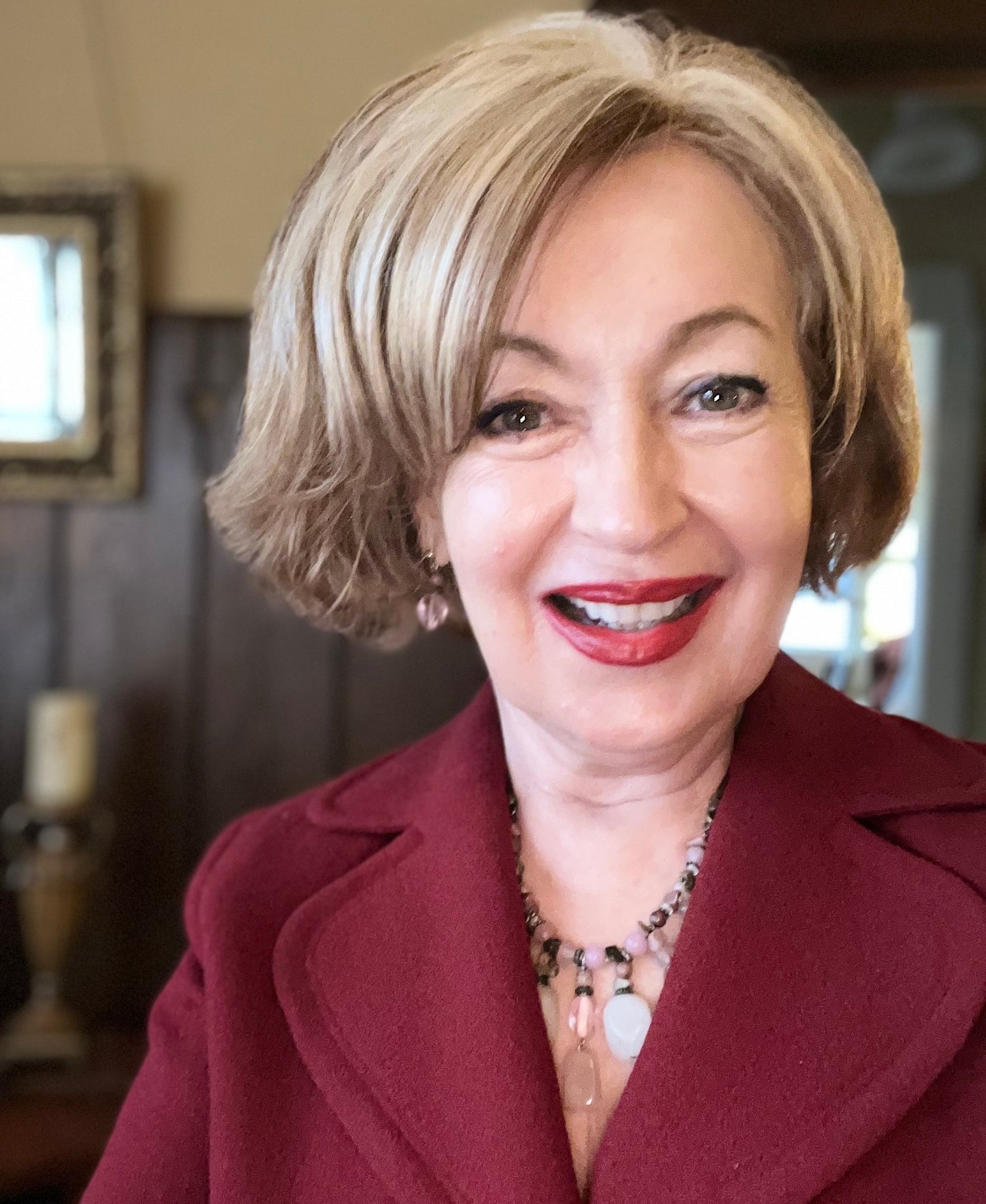 Photo of Dawn Morningstar, creator of Radiant Face 18. She has light brown hair and is wearing a red jacket and rose quartz necklace.