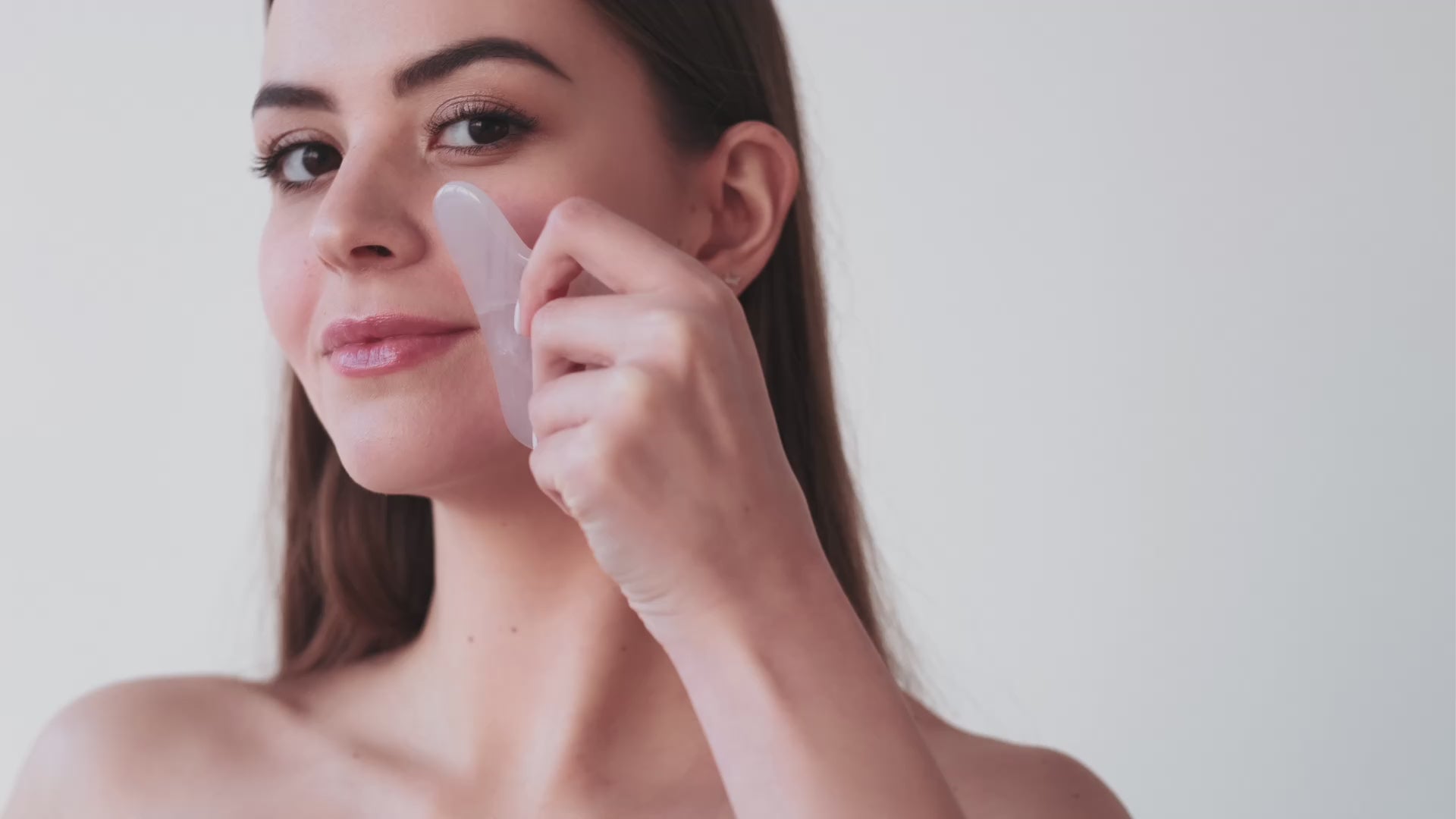 Video of woman using a rose quartz gua sha glow stone